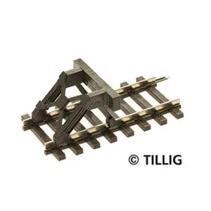 Een gedetailleerde foto van een Tillig modelspoor stootjuk op een kort stuk rails met houten bielsen, gezien vanuit een verhoogd hoekstandpunt op een witte achtergrond. Het juk is donkergrijs/zwart met koperkleurige klinknageldetails en twee prominente witte buffers.